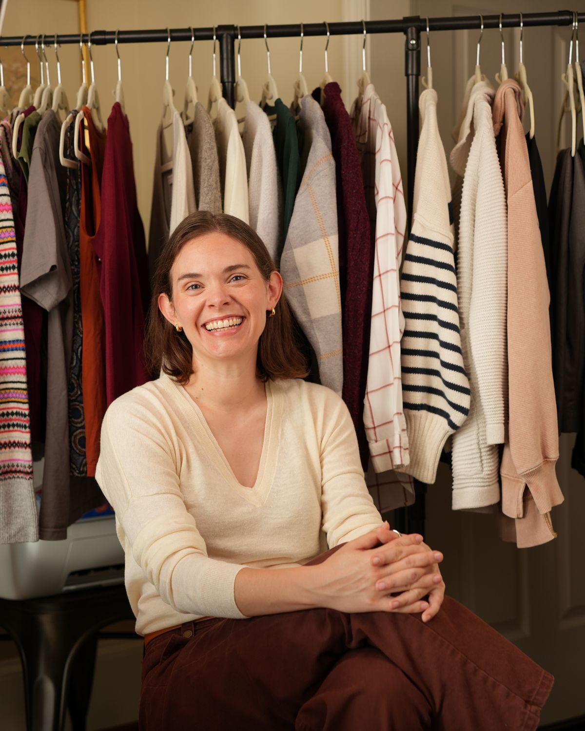 Lee Mullins seated in front of a rack of her own clothes